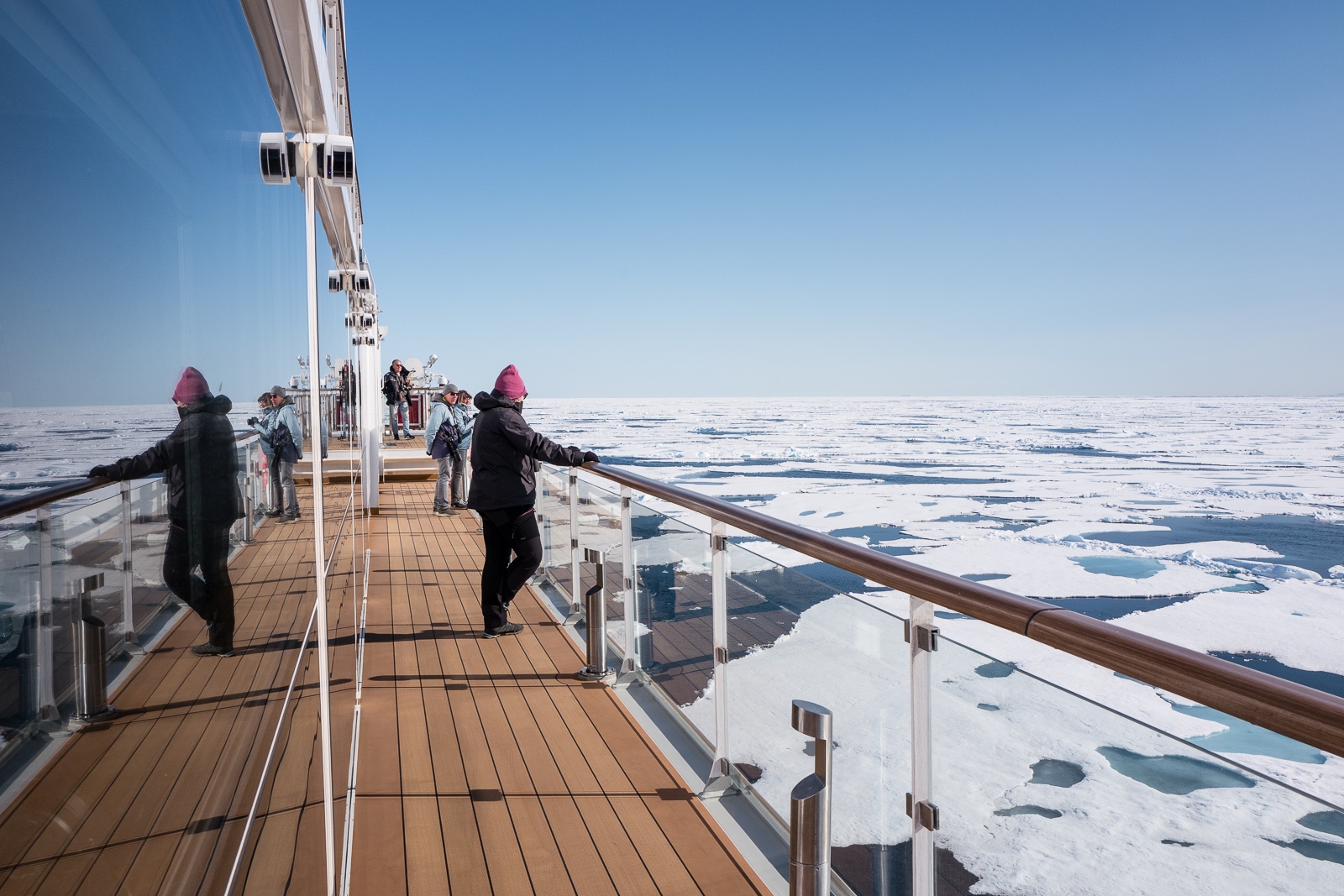 A person stands on deck admiring the ice from the Ocean Albatros Arctic ship 