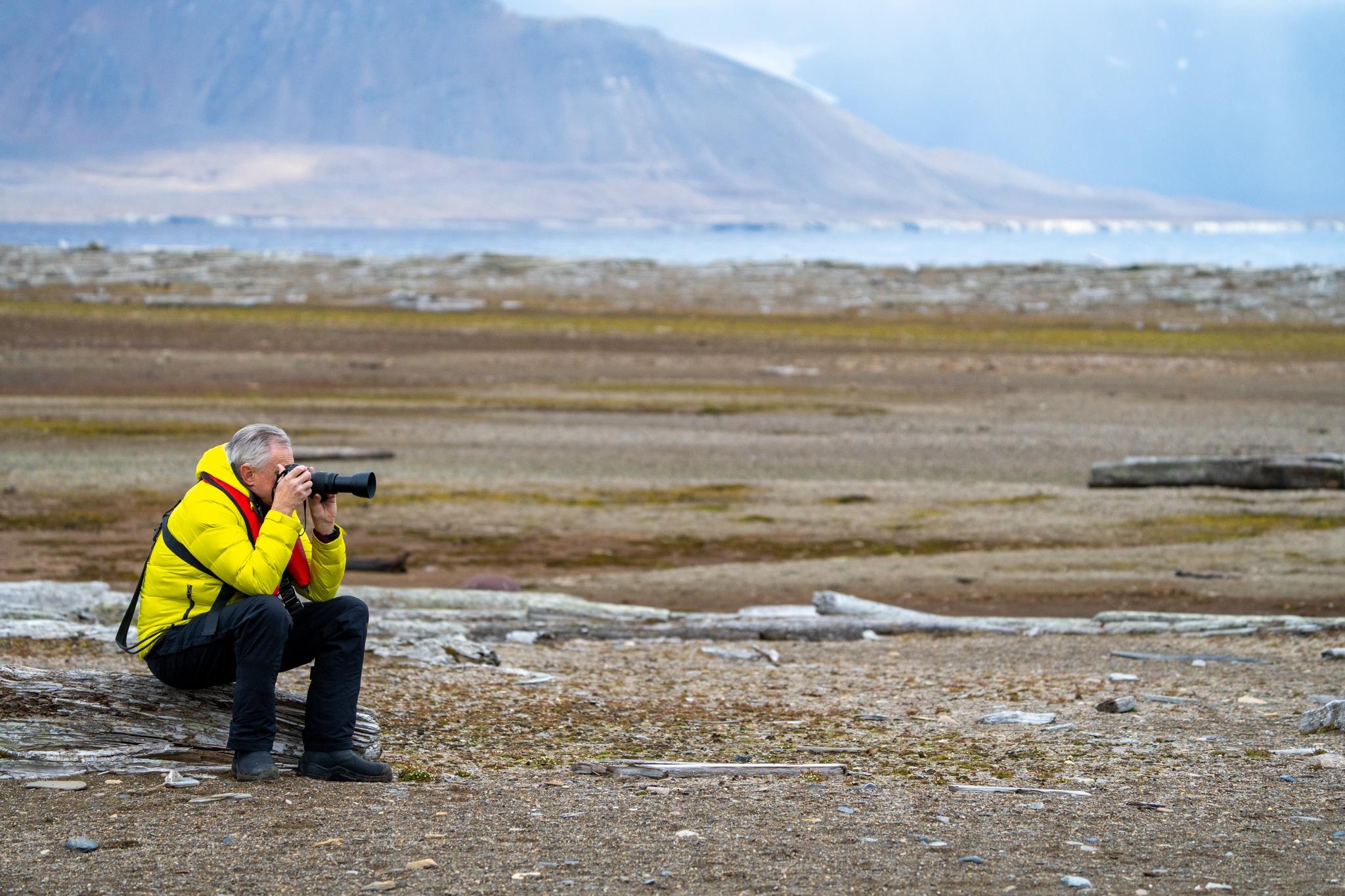 A man sits down while taking a picture in Svalbard