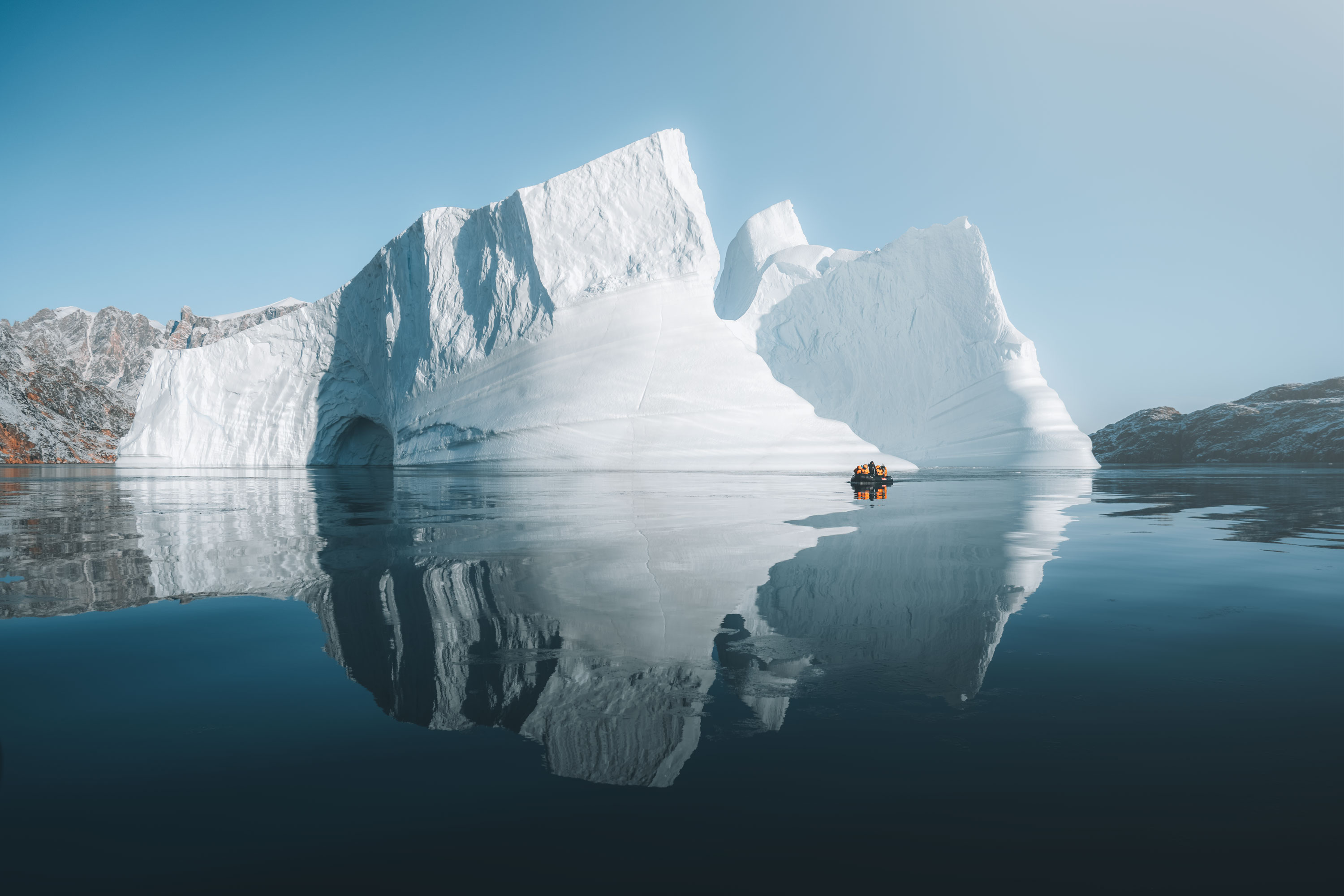 Zodiac dwarfed by an iceberg in Scoresbysund, Greenland