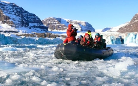 A zodiac cruises through the ice in East Greenland