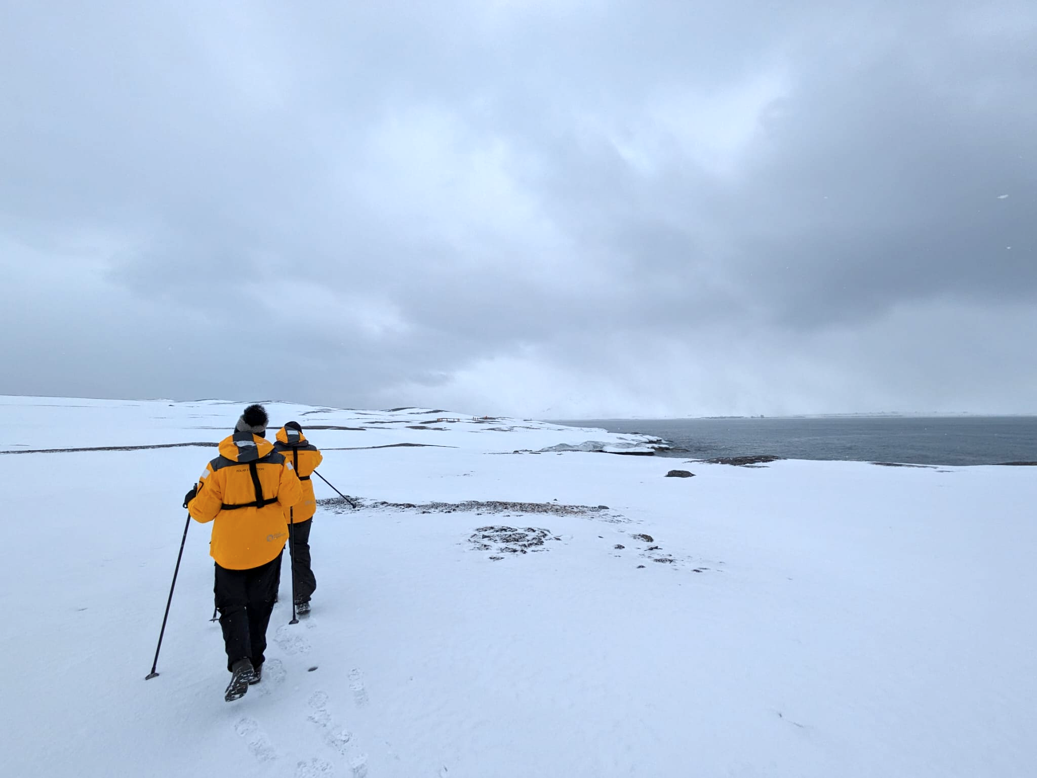 Two people wander through Arctic snow