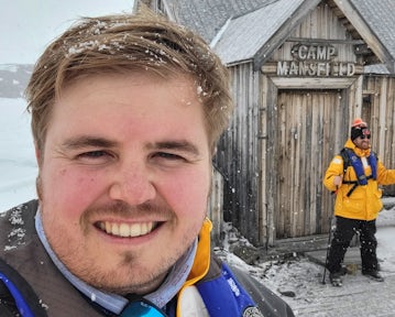 Swoop team member Nardus smiles in front of Camp Mansfield hut in the Arctic