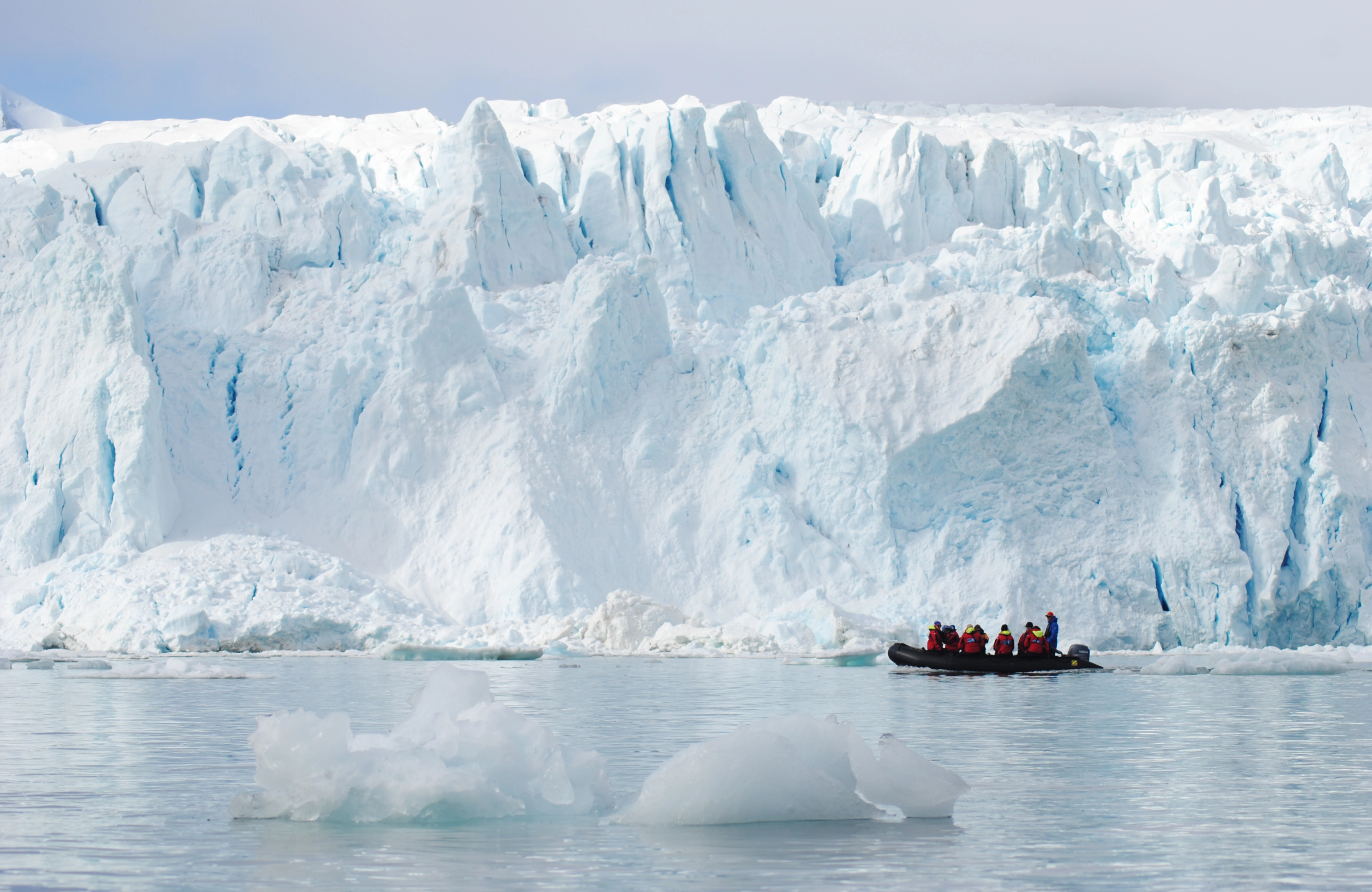 A zodiac cruises beside Monaco glacier, Svalbard