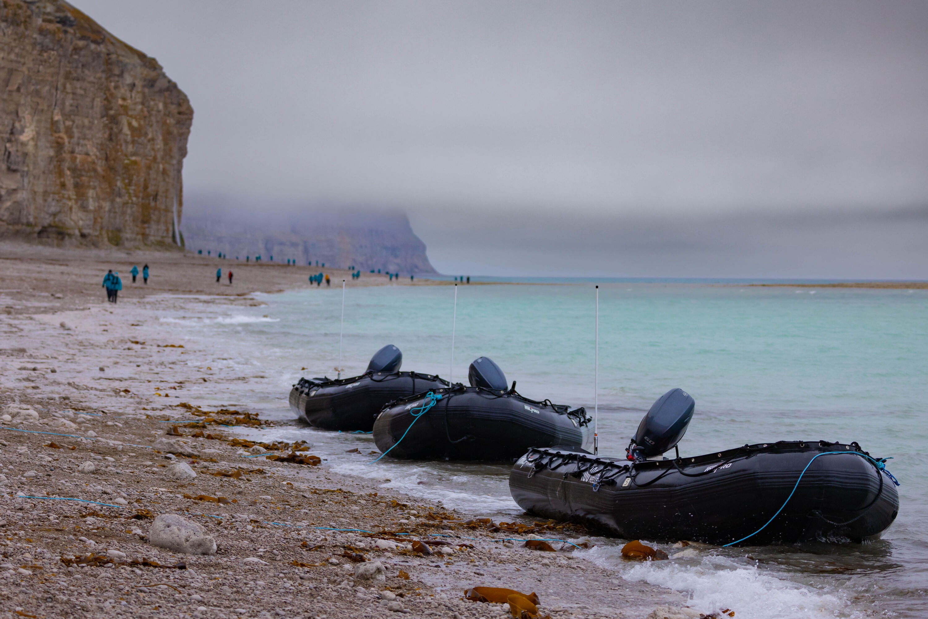 Zodiac boats sit and wait at the shore for passengers exploring remote Arctic scenery