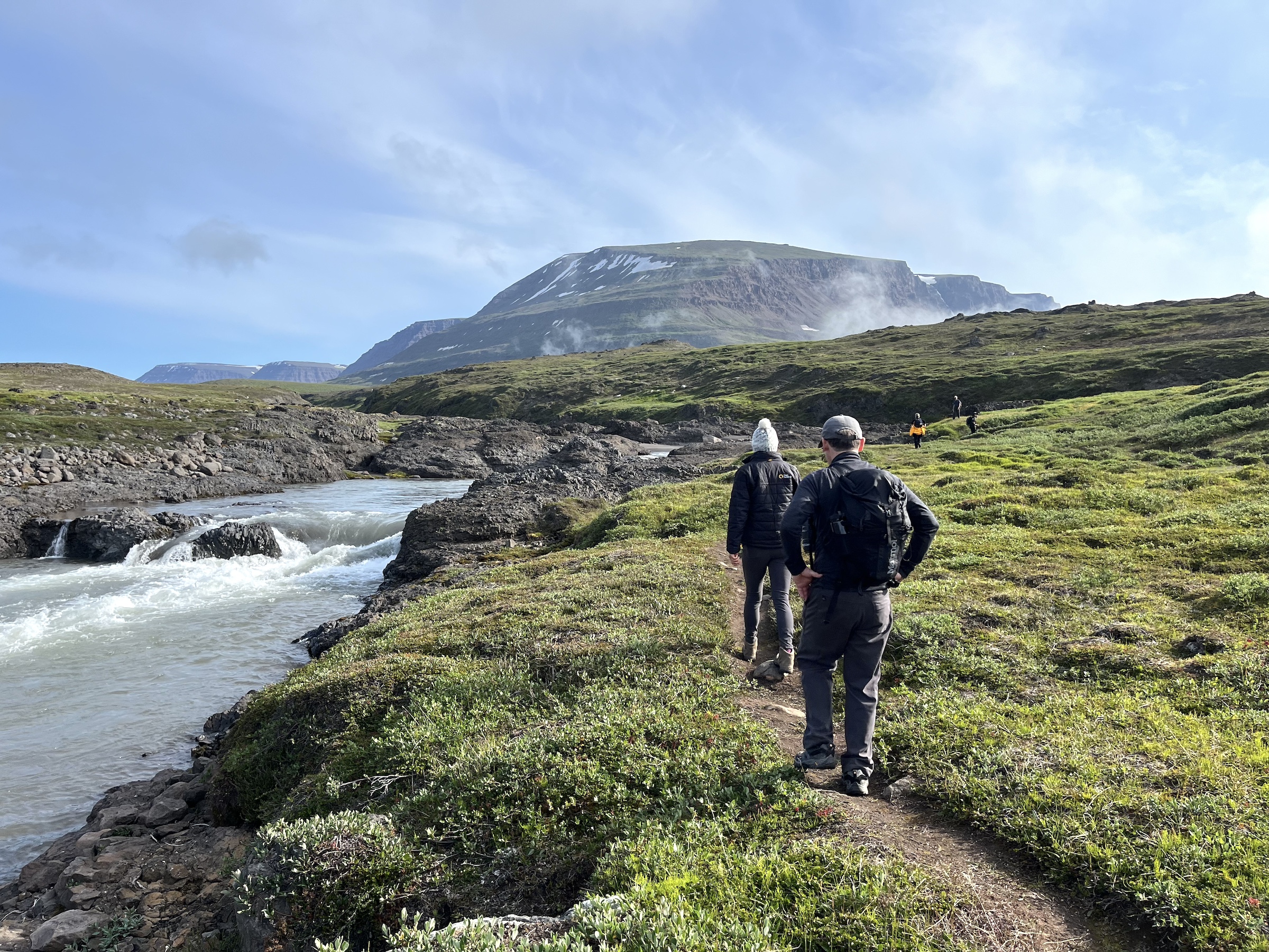 Two people hike in the lush landscapes of West Greenland