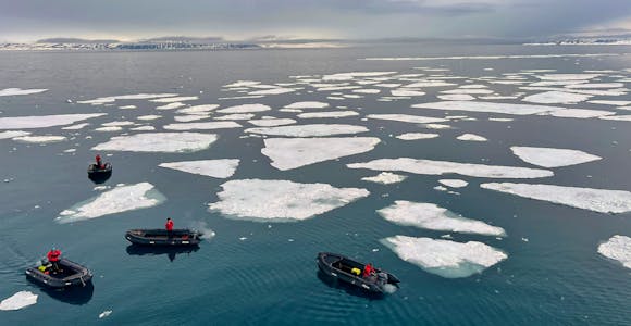 Zodiac boats glide around the ice in Svalbard